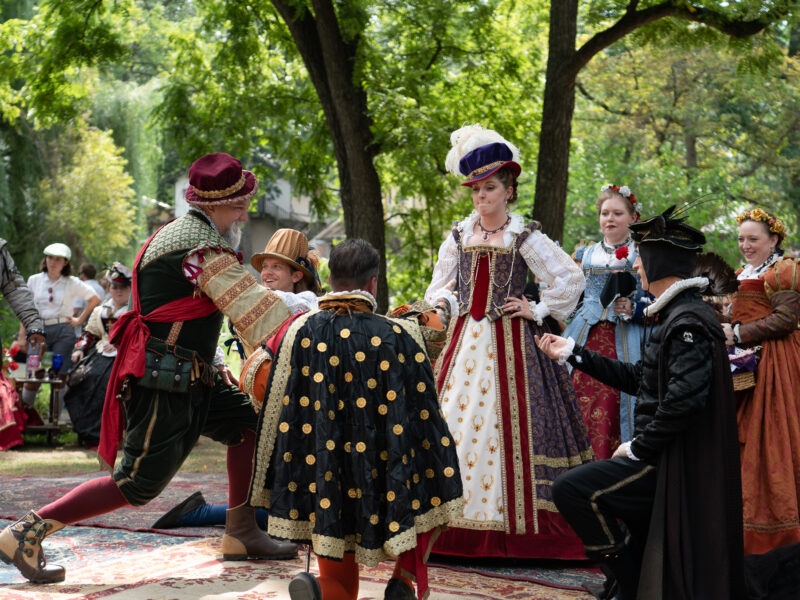 Men kneel around Queen Elizabeth during a renaissance faire