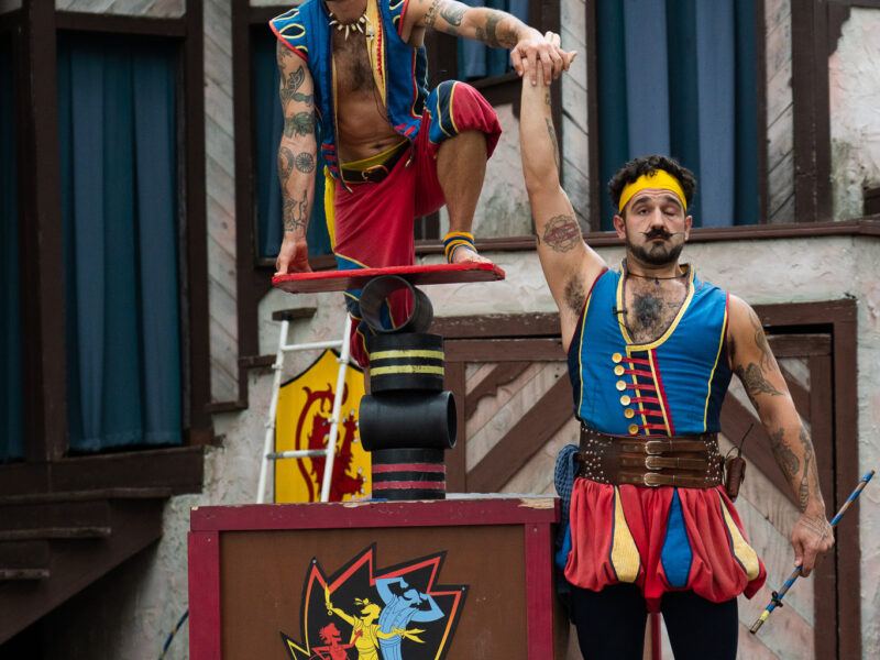 Two acrobats make faces while holding hands