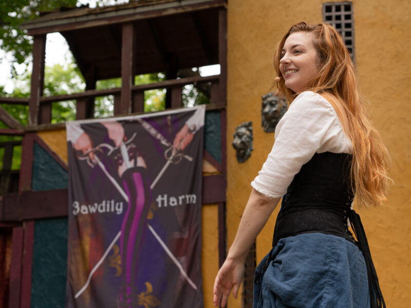 A woman in a swordplay show smiles on stage