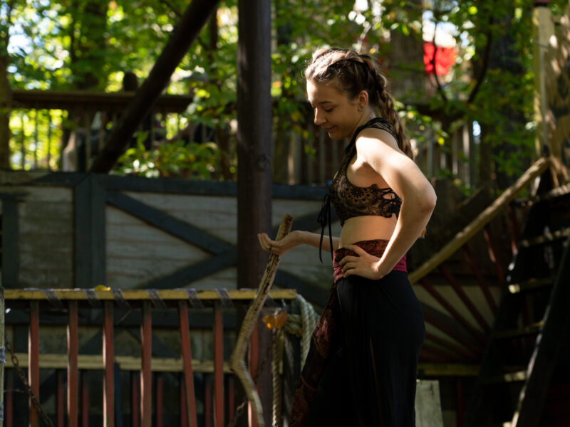 A woman swings a large stick at a swordplay show