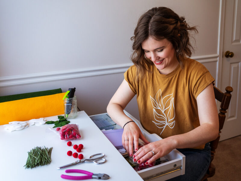 A woman opens the drawer of her craft desk.